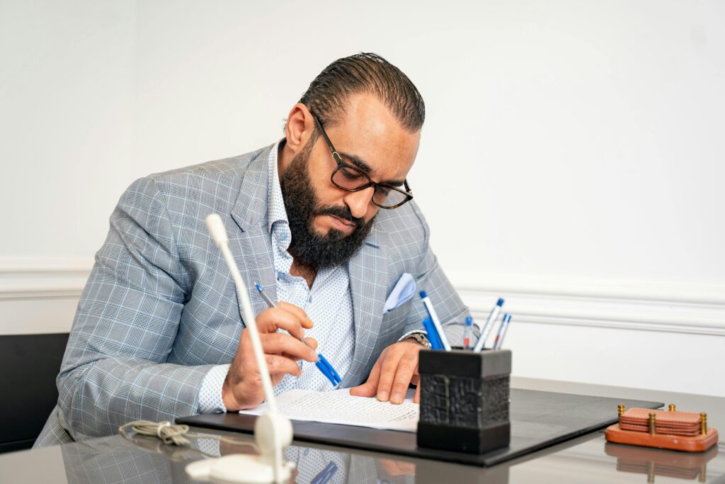 Professional bearded man in suit writing in modern office setting.